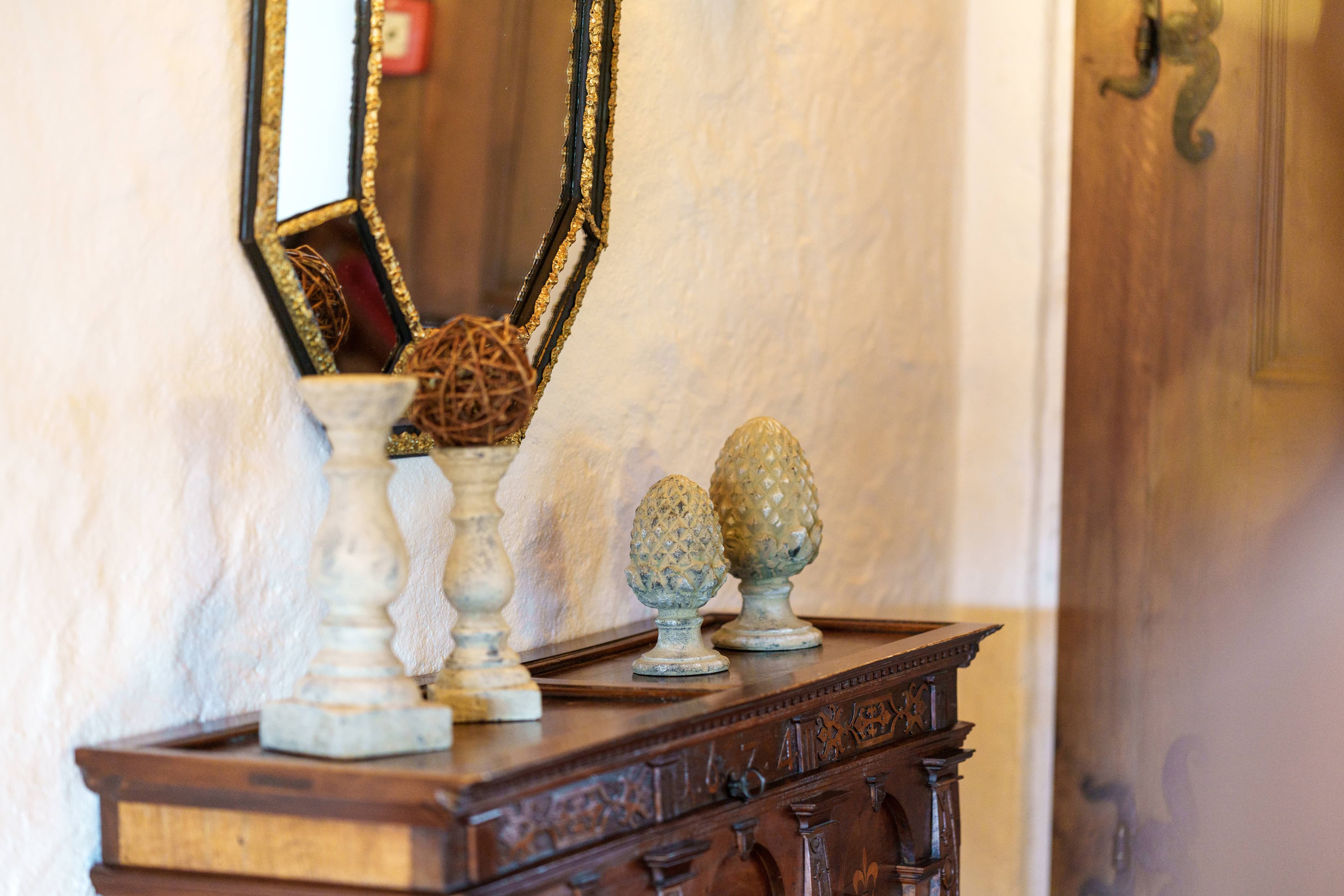 A decorative table in the Hotel Kreuz with candle holders, decorative objects, and an antique mirror on the wall.